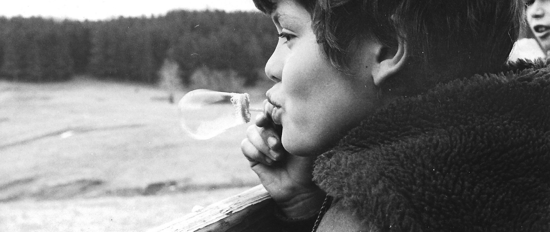 Closeup of a child blowing a bubble, overlooking Belwin's Education Center property. (black and white historical photo.)