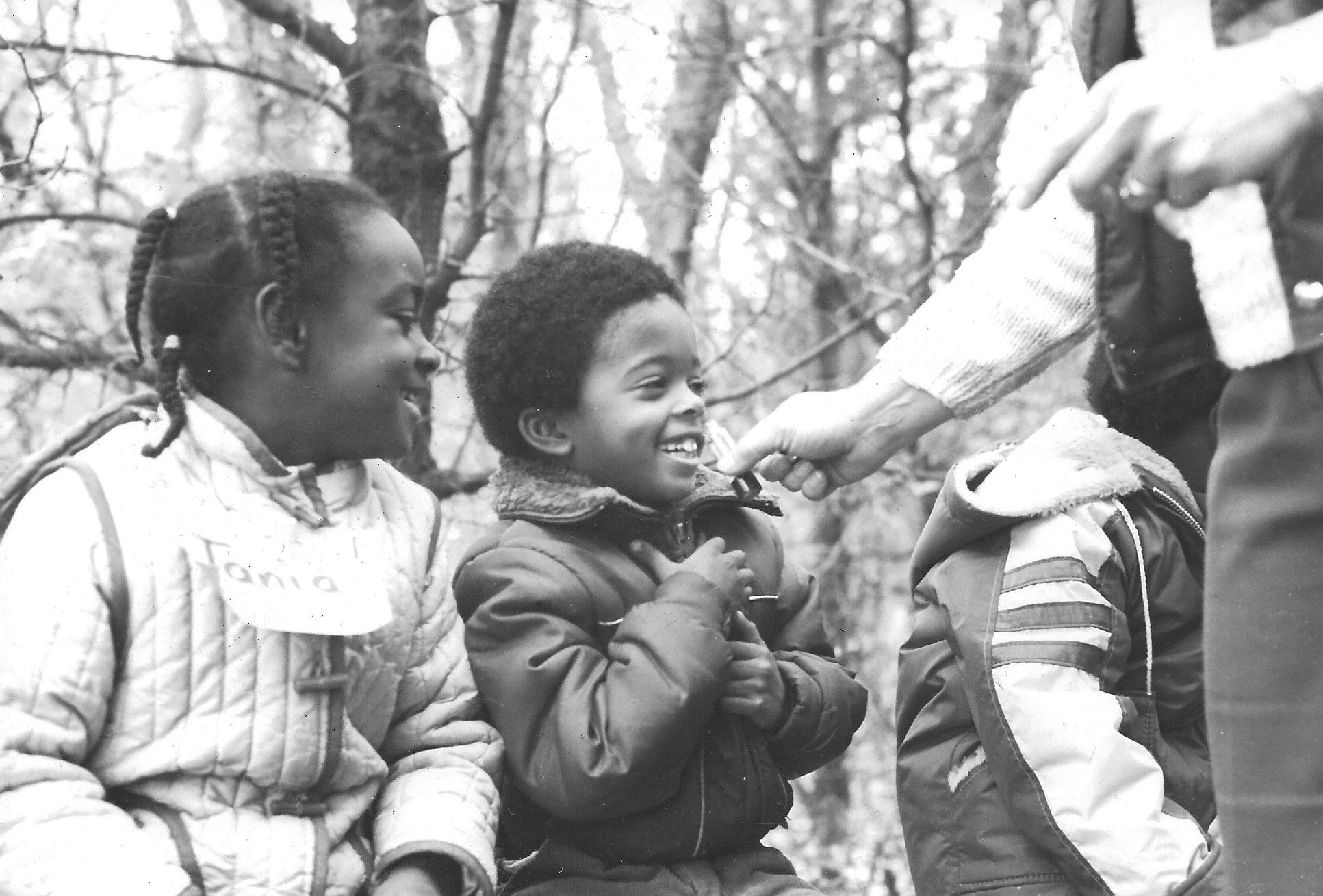 Two children wearing nametags and laughing. (Black and white historical photo.) 