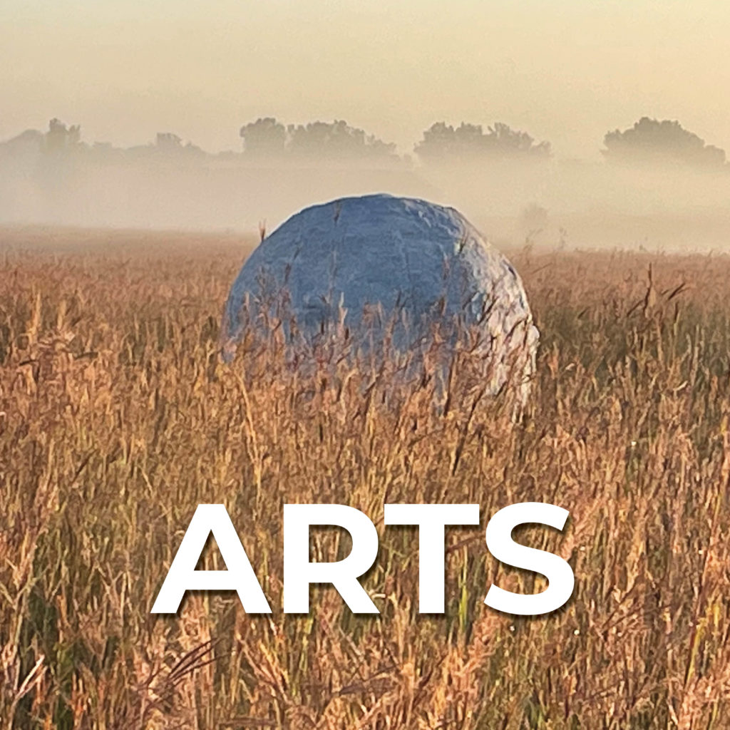 Round sculpture in prairie; text that says "Art"
