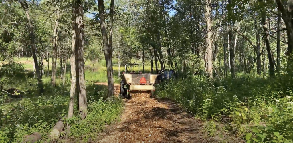 Wood chip machine spreading wood chips on forest path